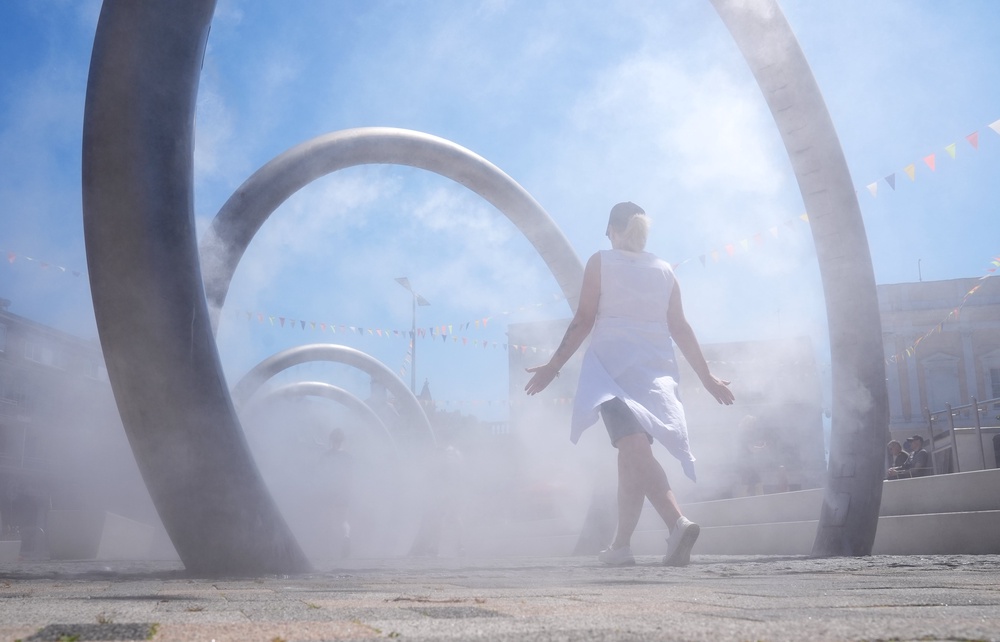 A woman walks through a water feature spraying a fine mist to cool off in Dover, Kent (Gareth Fuller/PA) (PA Wire)