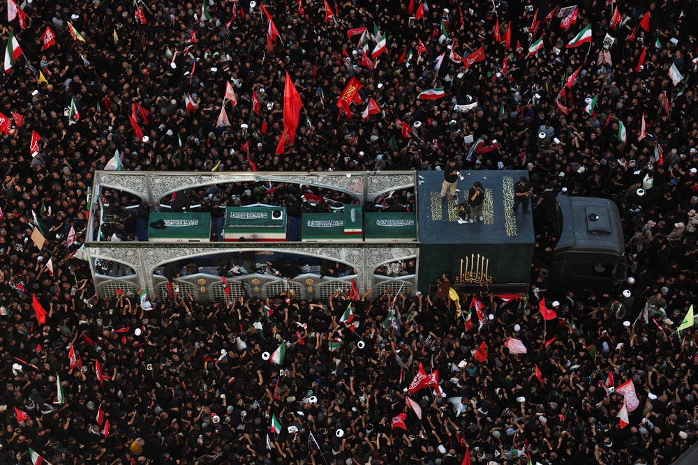 Mourners gather around a vehicle transporting the coffin of Iran's late supreme leader Ayatollah Ali Khamenei (Reuters)
