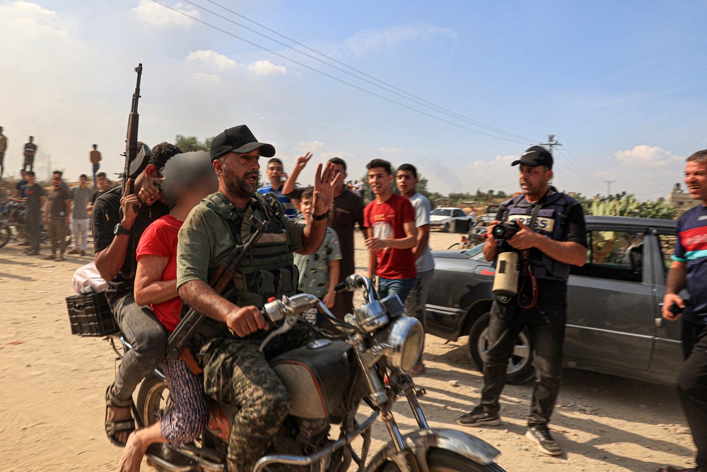 Palestinian militants transport a reportedly captured Israeli woman by motorcycle, in Khan Yunis in the southern Gaza Strip. (AFP via Getty Images)