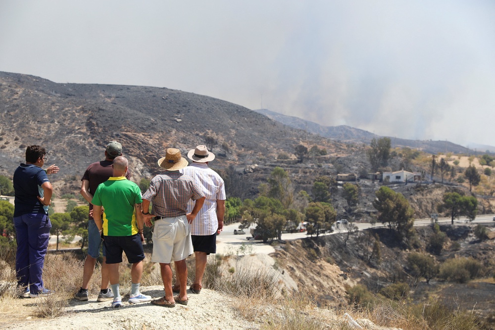 Residents in Almocaizar watch as smoke rises from the wildfire (Reuters)