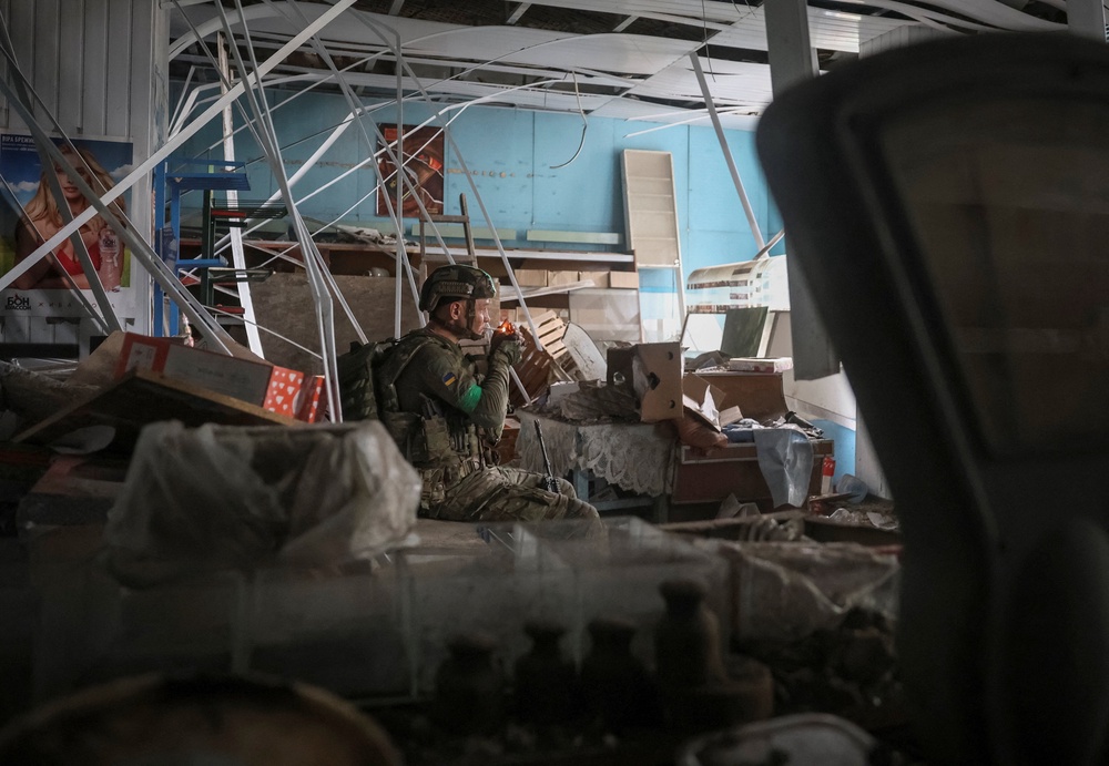A Ukrainian serviceman rests inside a damaged store during his combat mission in the frontline town of Druzhkivka, in Donetsk region, on 9 July (Reuters)