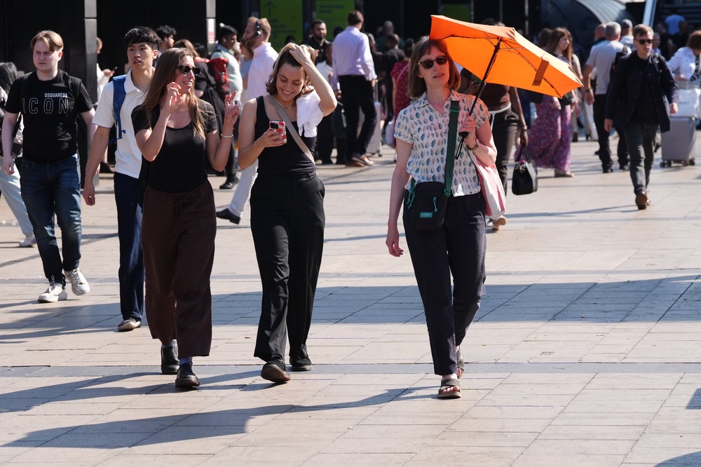 A woman using an umbrella for shade near Euston Station in central London (Jonathan Brady/PA) (PA Wire)