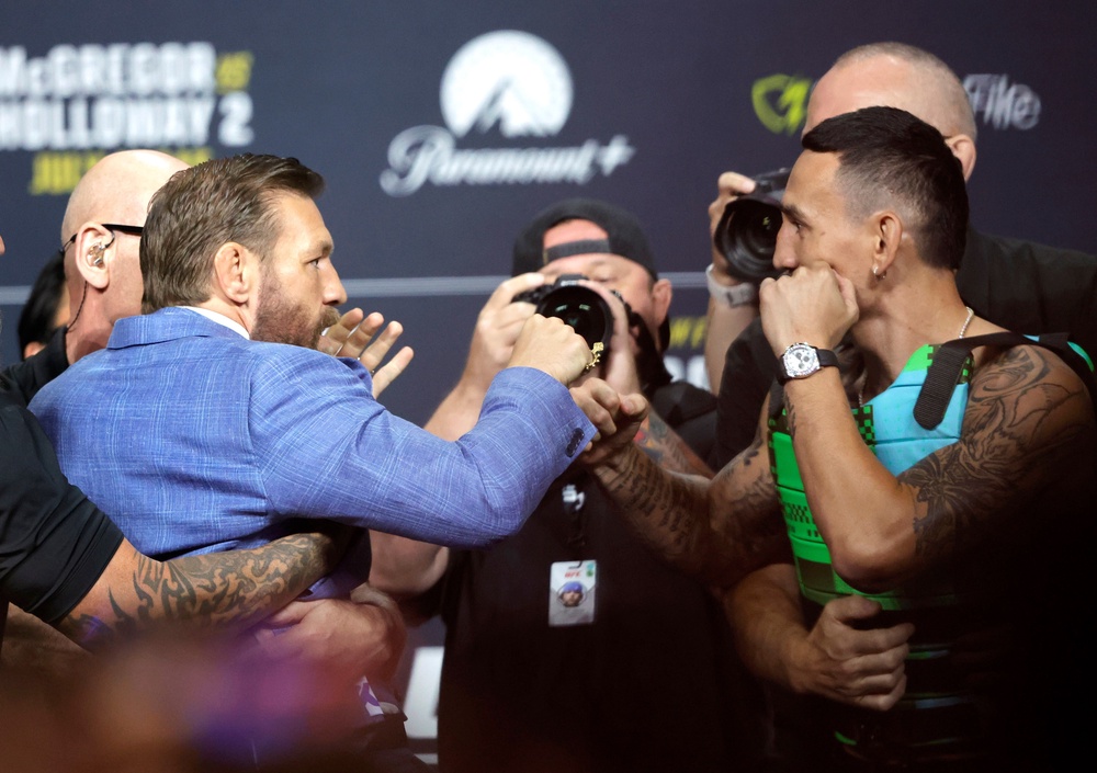 Conor McGregor (left) and Max Holloway pulled apart by security at their press conference (AP)