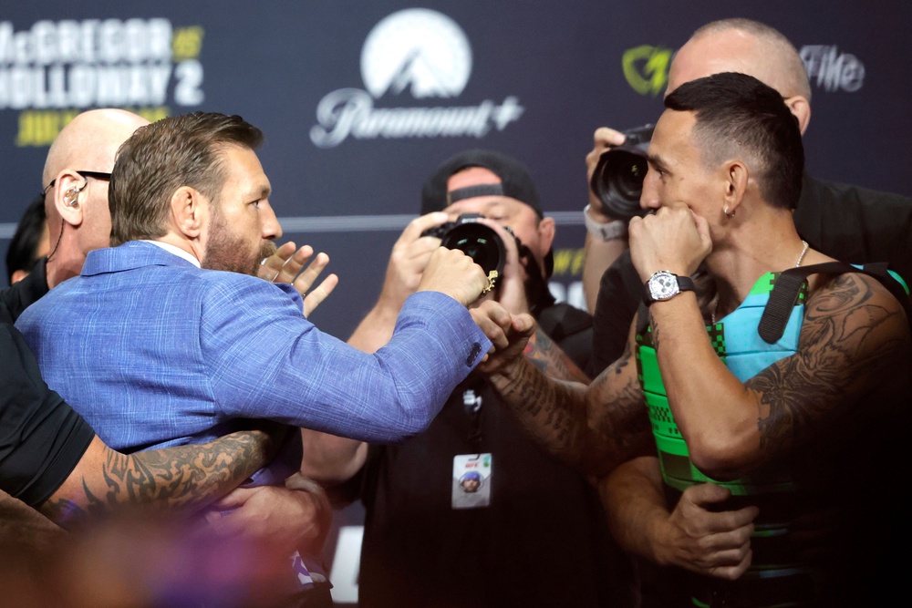 Conor McGregor (left) and Max Holloway pulled apart by security at their press conference (AP)