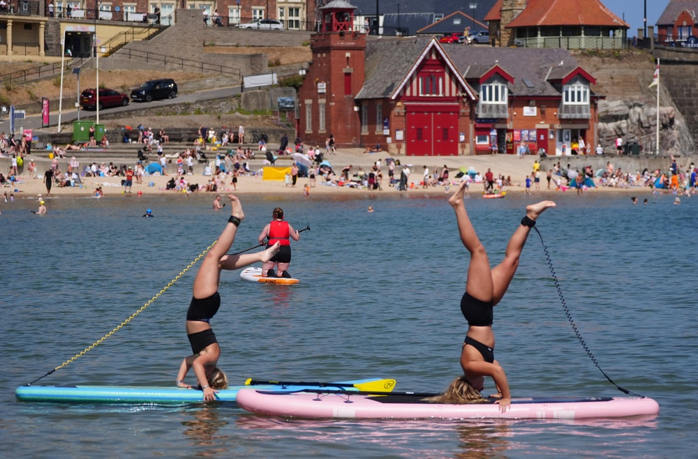 Paddleboarders Olivia Selby, 20, and her sister Abbie Selby, 17, enjoying the hot weather on the coast at Cullercoats Bay in North Tyneside (Owen Humphreys/PA) (PA Wire)