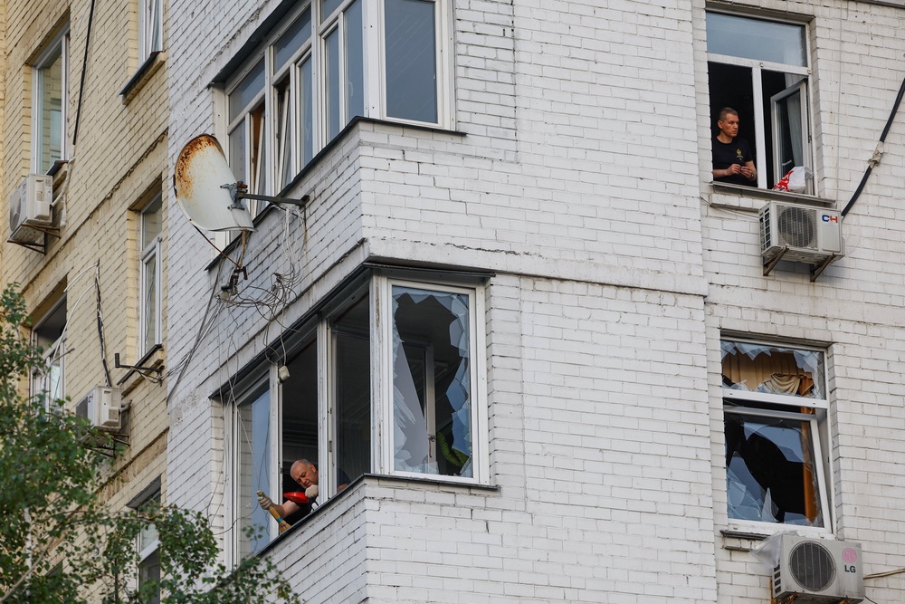 Residents remove pieces of glass from broken windows of their apartments, which were damaged during Russian missile strikes on Kyiv (Reuters)