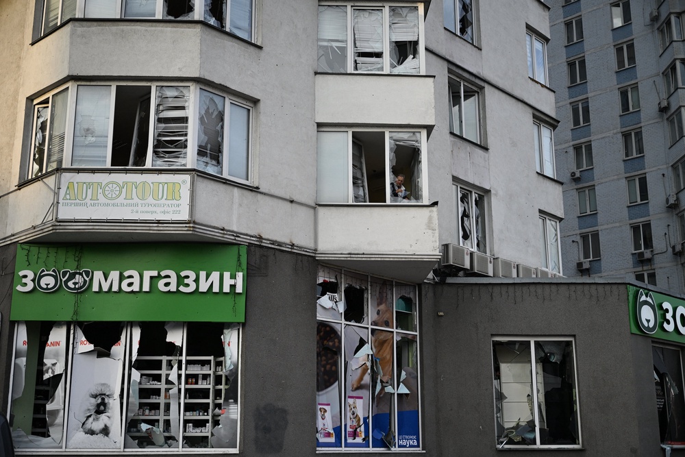 A resident clears shattered glass in a multistorey residential building (AFP/Getty)