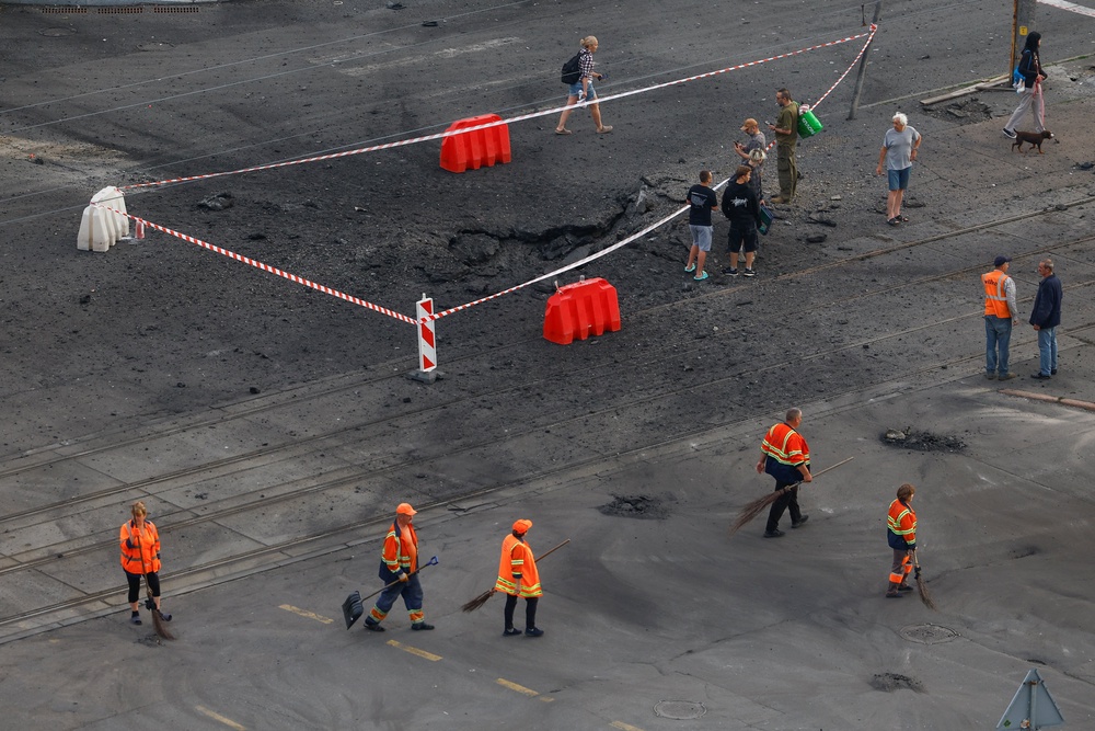 Residents gather next to a crater that appeared after Russian missile strikes (Reuters)