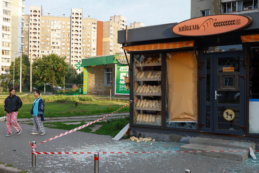 Teenagers walk next to a bakery shop damaged during Russian missile strike (Reuters)