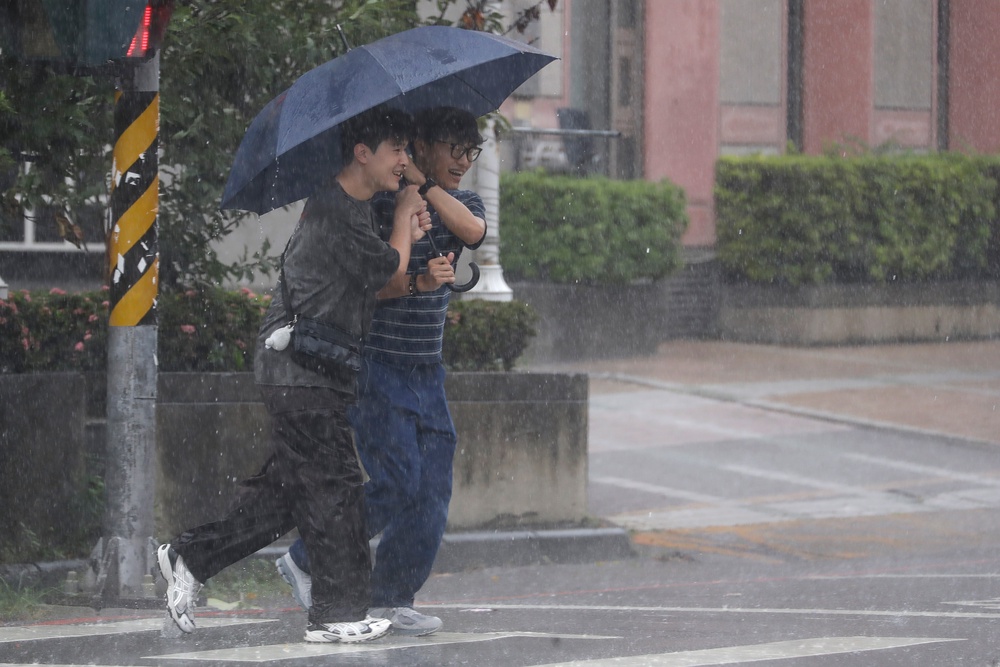 People make their way through rain caused by Typhoon Bavi in Taichung, Taiwan (AP)