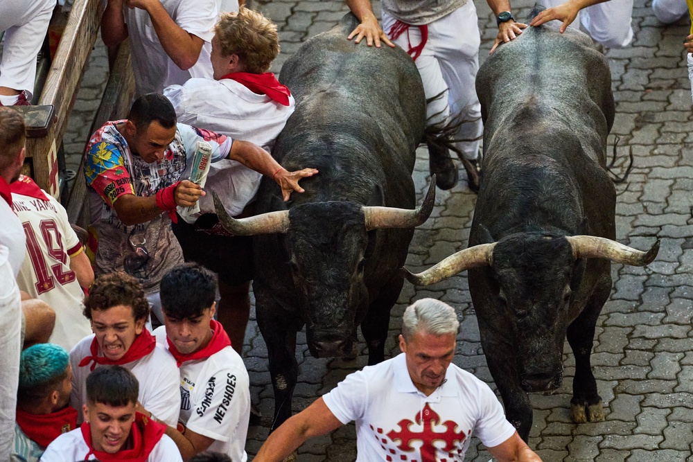 Revelers run alongside Jose Escolar's fighting bulls during the fifth running of the bulls at the San Fermín festival in Pamplona, Spain, Saturday, July 11, 2026. (AP Photo/Miguel Oses) (AP)