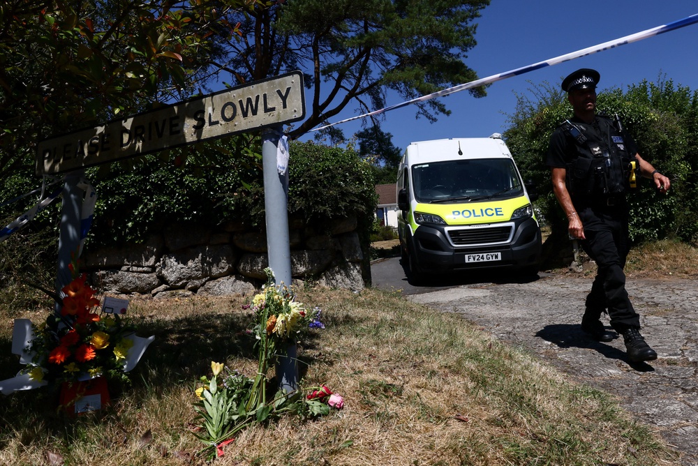 A police officer walks past flower tributes left outside the home of 78-year-old former government minister Ann Widdecombe (Reuters)