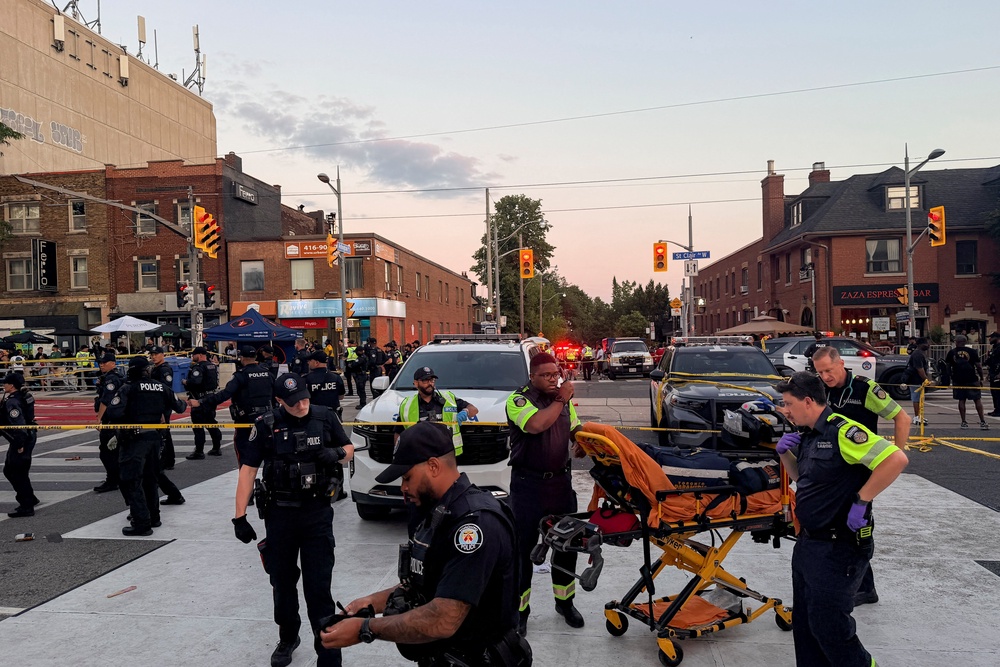 Police officers stand guard as emergency workers respond at the site of a deadly shooting at a salsa-themed street festival (Reuters)