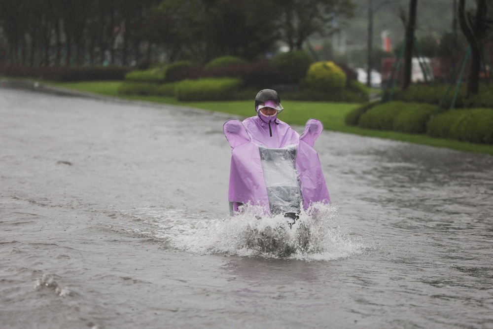 A person rides an electric scooter through a flooded road after heavy rain brought by Typhoon Bavi in Wenzhou, Zhejiang province, China (Reuters)