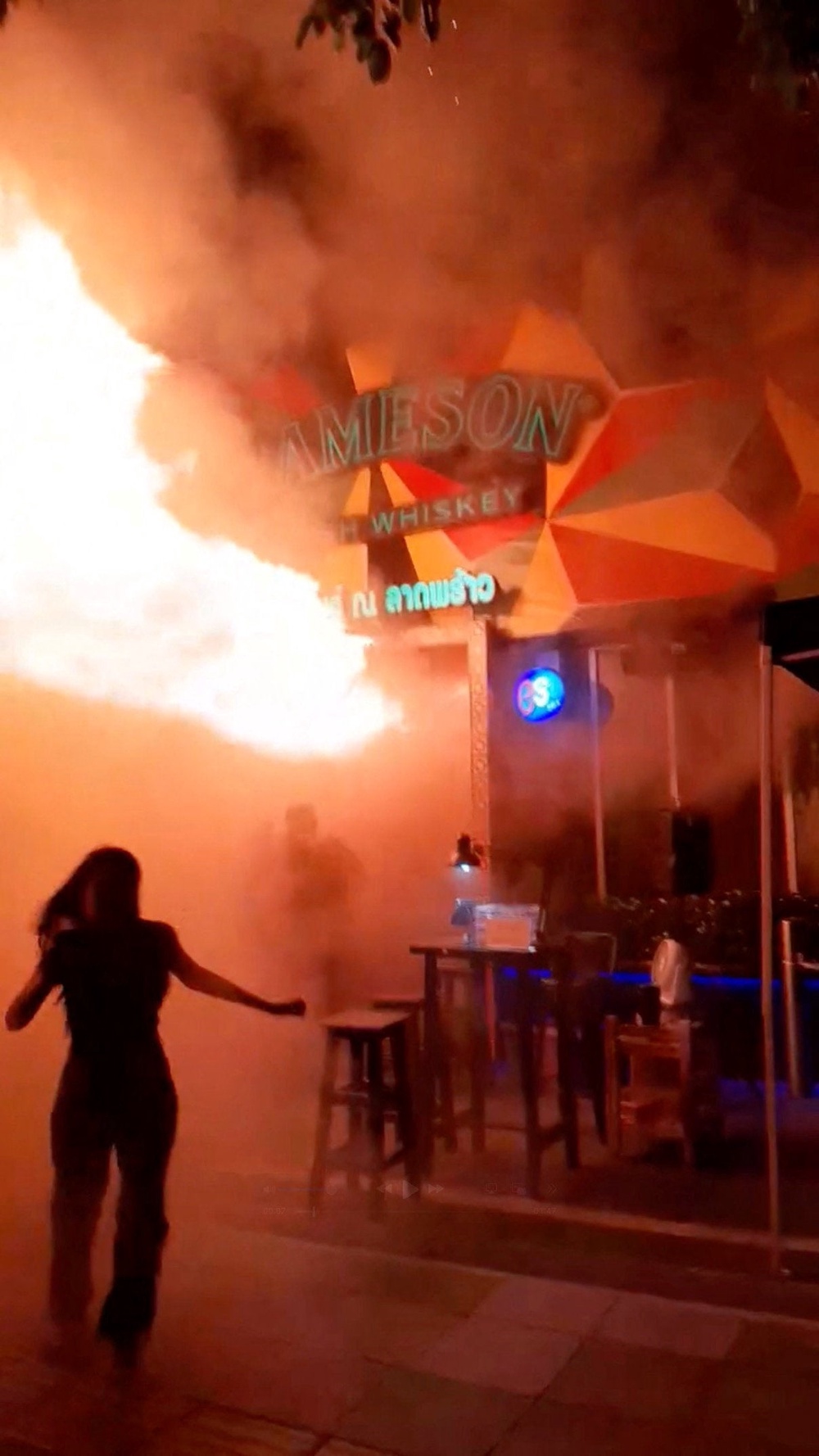 People run as flames rise at a pub in Bangkok, Thailand (Reuters)