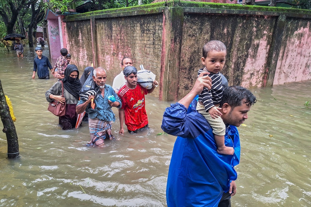 Residents wade through floodwaters after heavy monsoon rains in Chattogram (AFP/Getty)