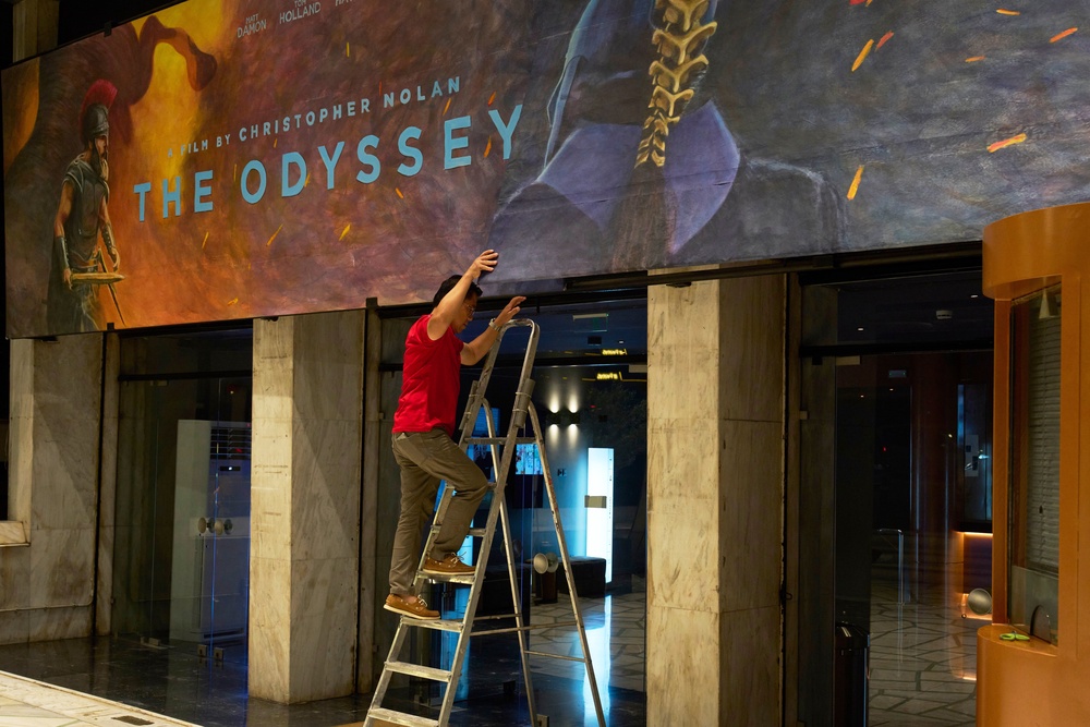 A worker installs a hand-painted billboard, painted by artist Virginia Axioti, for Christopher Nolan's upcoming film 