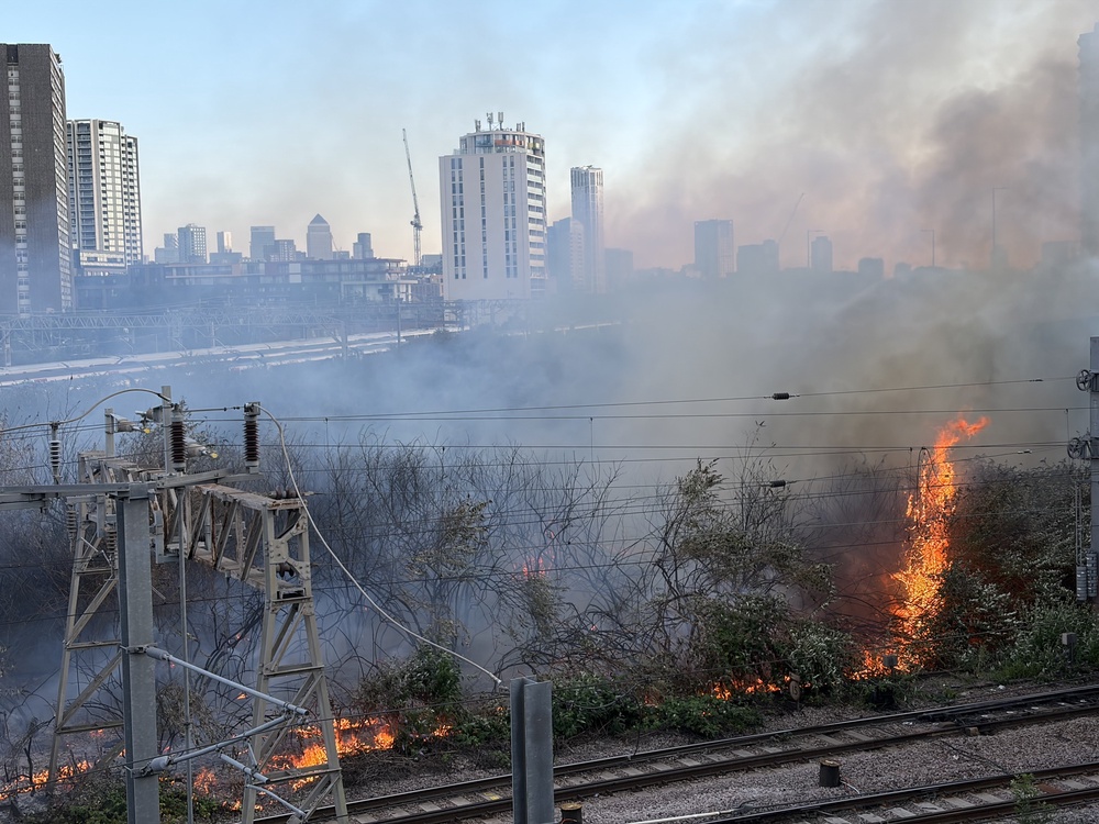 Shrubbery caught fire along rail lines near Stratford Station in east London on Friday (James Weech/PA) (PA Wire)