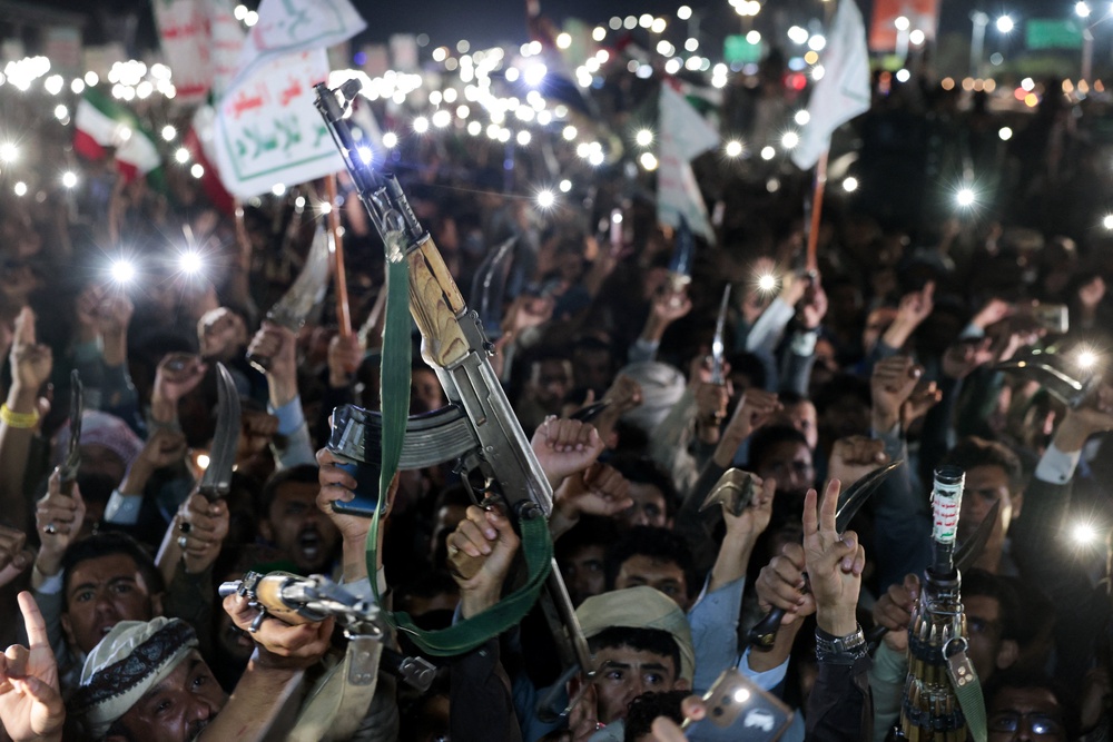 Houthi supporters hold up weapons as they demonstrate against airstrikes on Sanaa International Airport (Reuters)