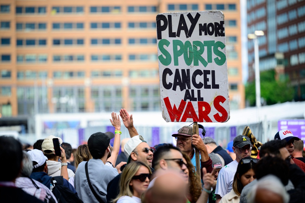 A man holds a ‘Play no Sports, Cancel all Wars’ placard outside Lumen Field (Getty)