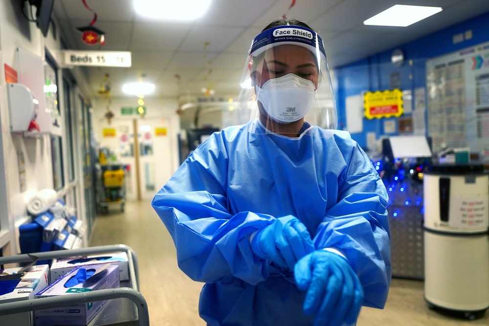 A nurse puts on full PPE on a ward for Covid patients at King’s College Hospital in 2021 (Victoria Jones/PA) (PA Archive)