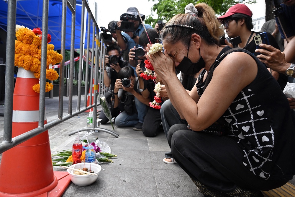 A woman, identified as Nid, prays for her deceased daughter Namtip Tubsook and her son-in-law Suwitcha Sirililung in front of the Rong Beer Na Lat Phrao bar in Bangkok on July 14, 2026 (AFP/Getty)