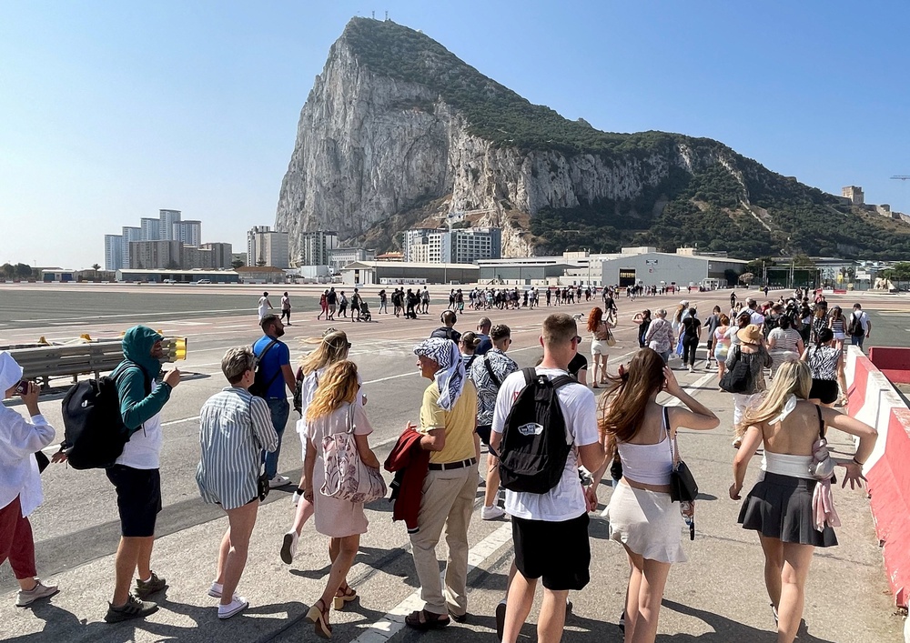 Tourists cross the tarmac of the airport in front of the Rock (Reuters)