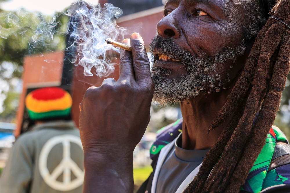 A Rastafarian smokes as they gather outside Milimani Law Courts, after the high court dismisses a Rastafarian case seeking to legalize marijuana, in Nairobi, Wednesday, July 15, 2026. (AP Photo/Andrew Kasuku) (Copyright 2026 The Associated Press. All rights reserved.)