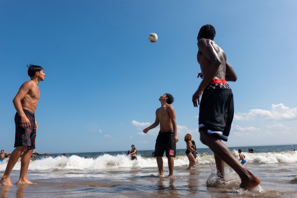 A group of teens play soccer at the beach at New York City’s Coney Island earlier this month. Experts say using happier images to tell stories about deadly heat can leave readers confused about the severity of its effects (Getty Images)