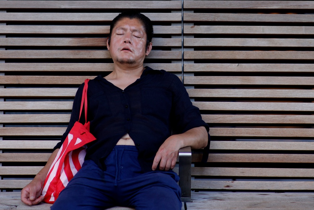 A man rests in the shade on a bench in New York City during this month’s heatwave. Experts recommend more negative or neutral images to tell stories about heat and climate change (AFP via Getty Images)