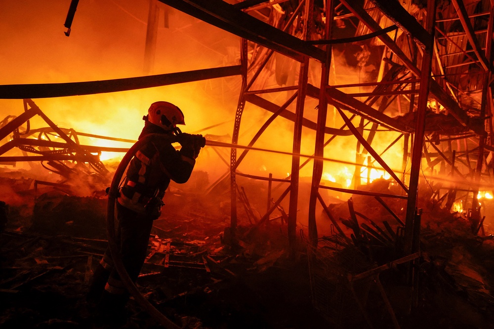 A firefighter works at a compound of a warehouse damaged during Russian missile strikes, amid Russia's attack on Ukraine, in Kyiv (Reuters)
