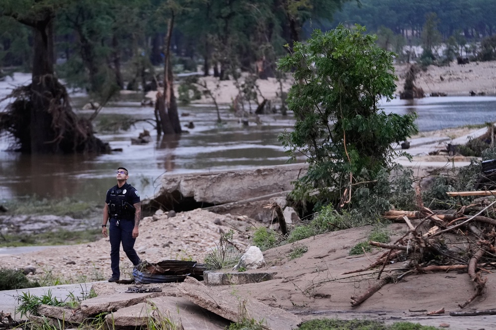 A police officer walks along the Guadalupe River after a series of storms on Friday, July 17, 2026 (AP Photo/Gerald Herbert)