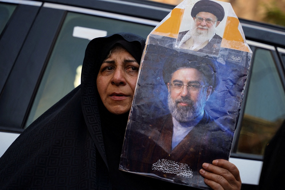 A woman holds a portrait of Iran’s Supreme Leader Mojtaba Khamenei and Iran’s late Supreme Leader Ayatollah Ali Khamenei (Reuters)