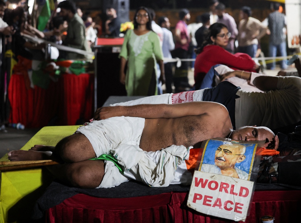 A supporter of the Cockroach Janta Party dressed as MK Gandhi sleeps at a protest site (Reuters)
