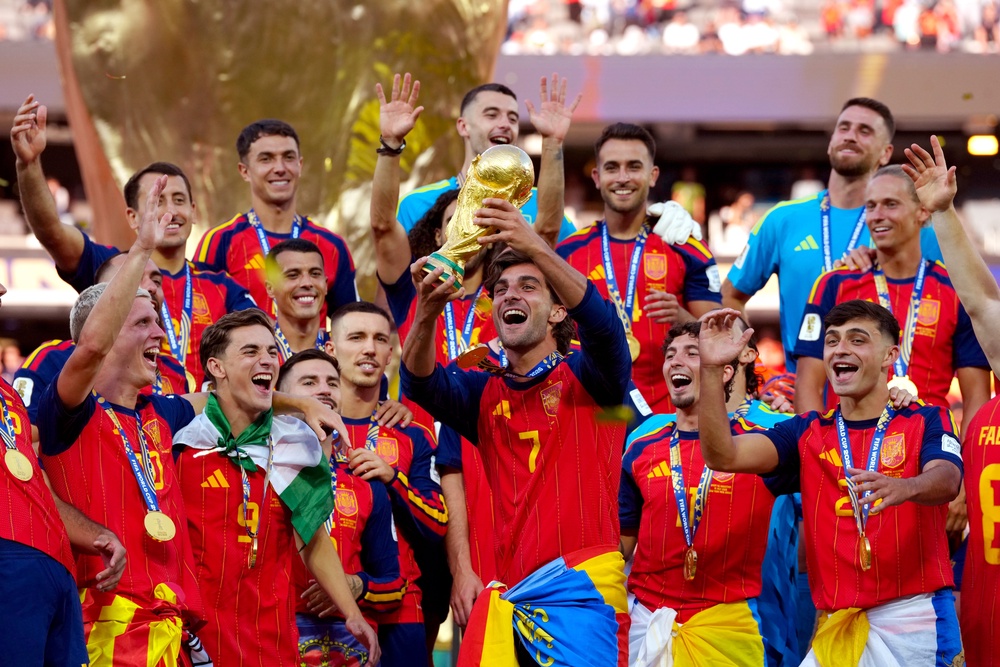 Spain’s Ferran Torres celebrates holding the world cup trophy alongside his teammates (PA)
