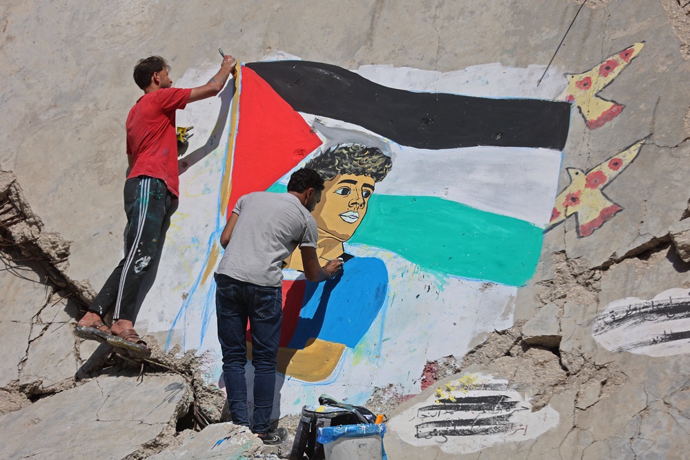 Palestinian artists paint a mural depicting football player Lamine Yamal waving a Palestinian flag during the Catalans' title parade, on the rubble of buildings destroyed during the war, at Shati (Beach) refugee camp in Gaza City on May 13, 2026. (AFP/Getty)