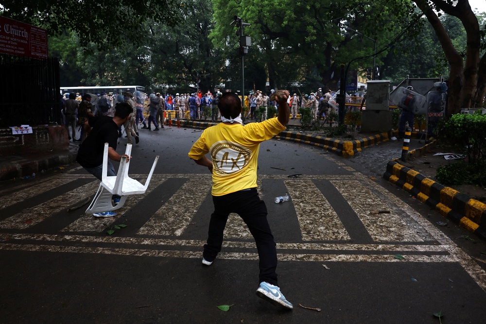 Demonstrators hurl a stone and a chair towards police (Reuters)