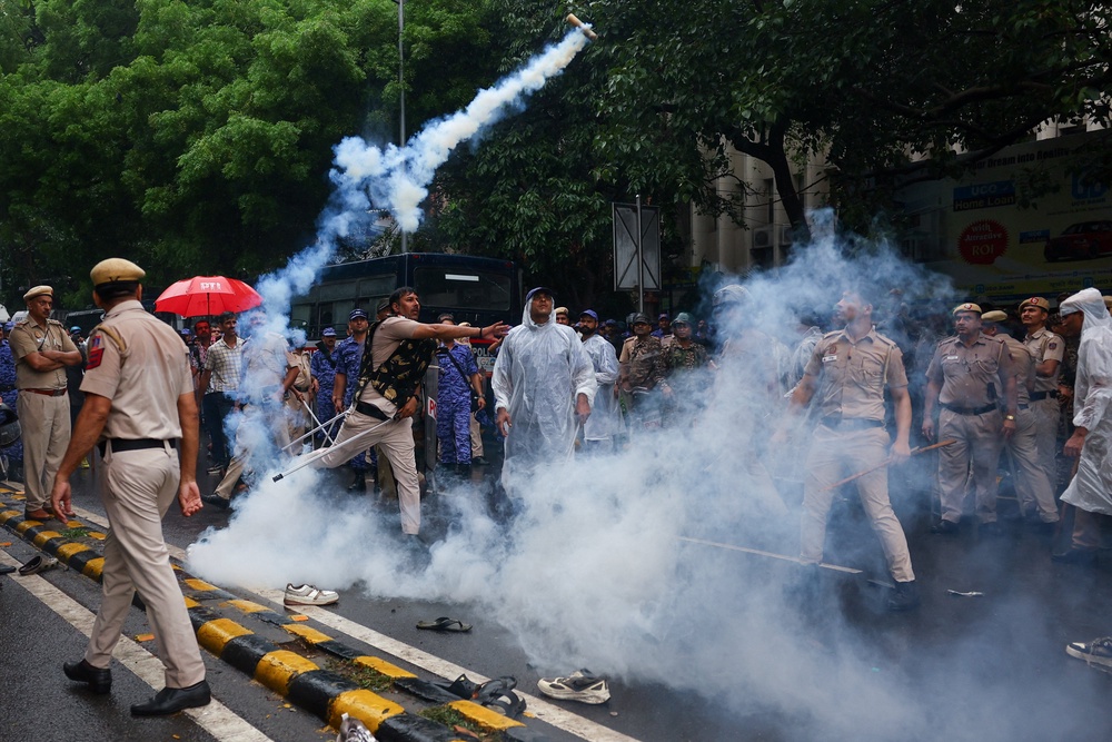 A police officer throws a tear gas canister towards protesters (Reuters)