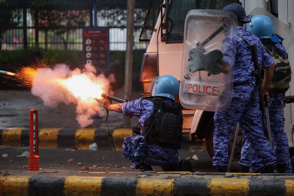 A member of the Rapid Action Force (RAF) fires a tear gas canister towards protesters (Reuters)