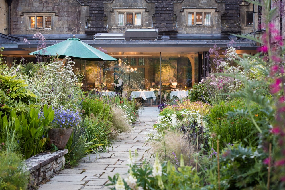 Gravetye Manor garden and glass fronted Michelin Star restaurant (Jodi Hinds/Gravetye Manor/PA)