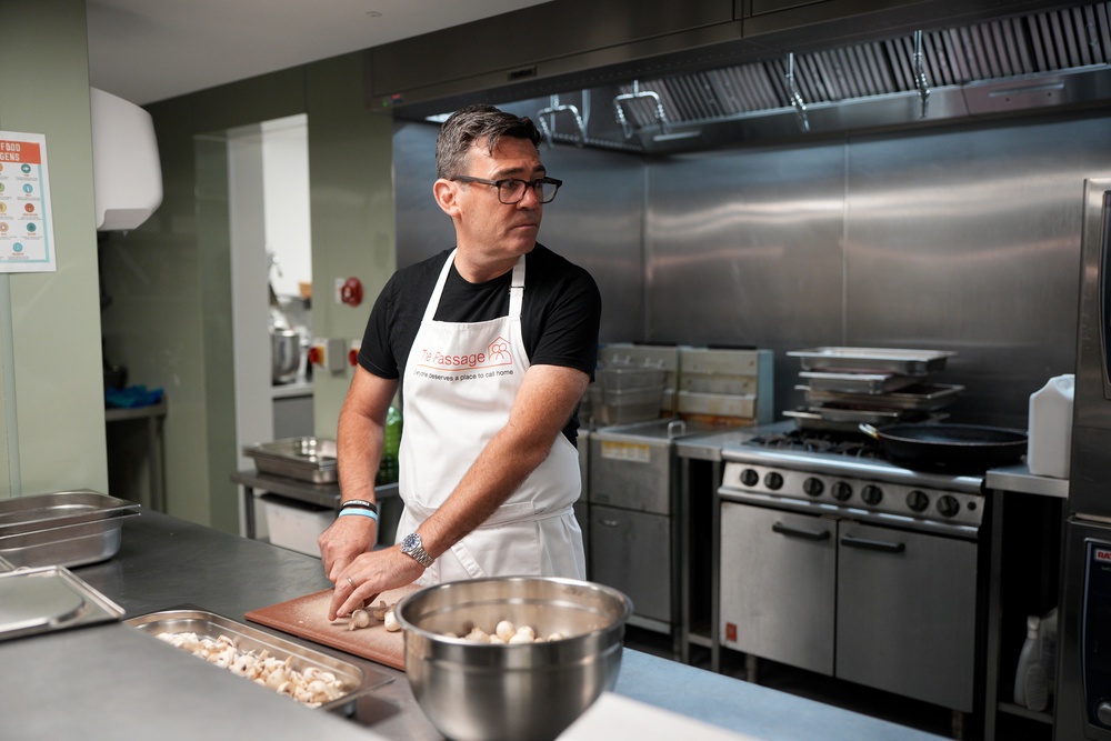 Andy Burnham helps prepare breakfast during a visit to The Passage Homeless Charity in London on Monday (AP)