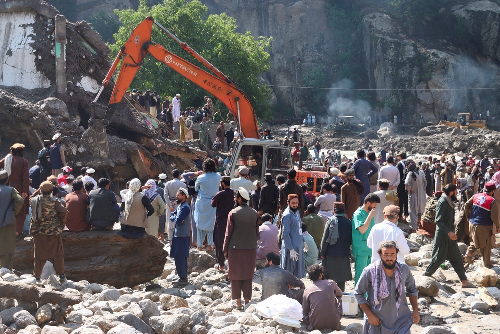 People gather as an excavator clears debris following flash floods in Parun, Nuristan, Afghanistan (Reuters)
