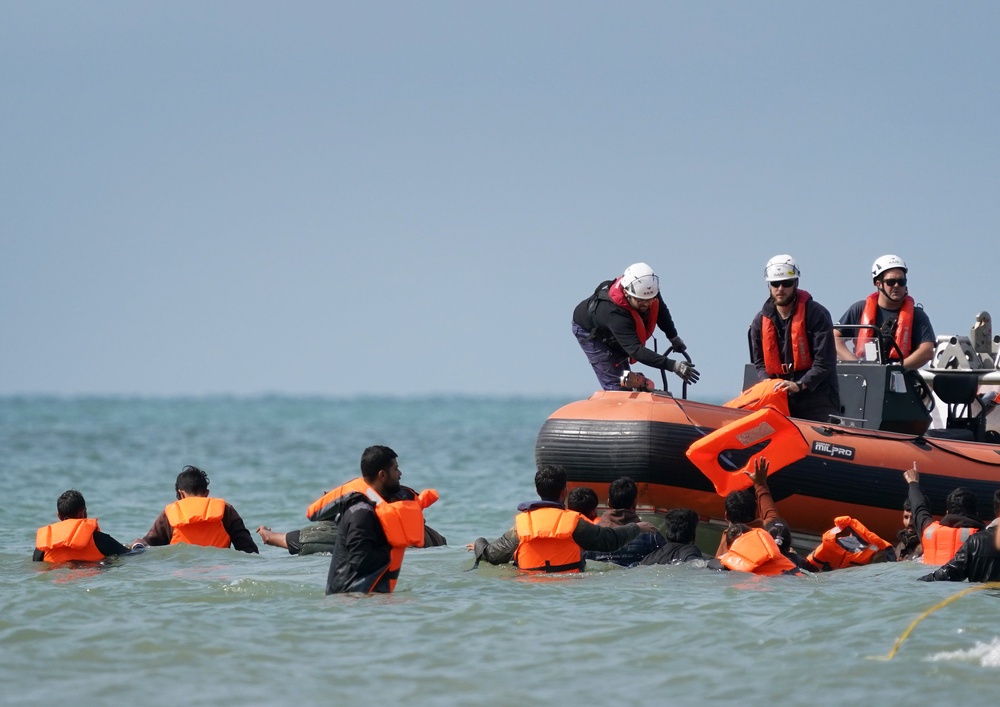 People thought to be migrants are handed life vests by French rescuers as they wade through the sea to board a small boat off the coast of Equihen-Plage (Gareth Fuller/PA) (PA Wire)