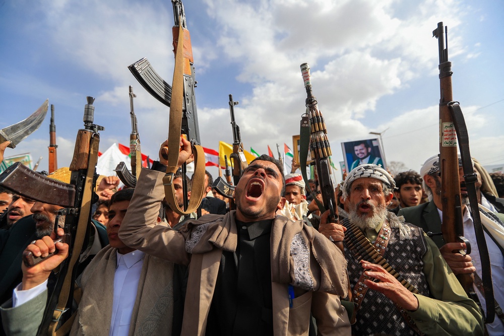 Armed Yemeni supporters of the Iran-backed Houthi movement brandish their weapons during a protest against US strikes (AFP/Getty)