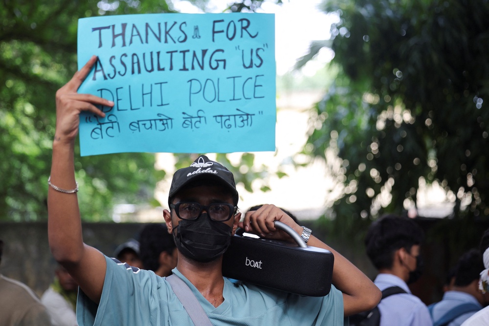 A protester hold placard mocking Delhi Police for assaulting the youth on ground demanding resignation of education minister Dharmendra Pradhan (Reuters)