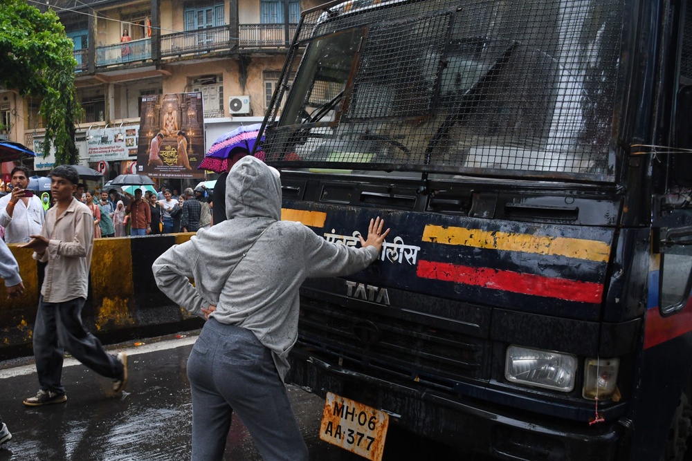 Rhiya Ahir, a model, blocks a police van carrying detained protesters during a demonstration demanding educational reforms as part of the Cockroach Janta Party's ongoing protest movement in Mumbai, India (AP)