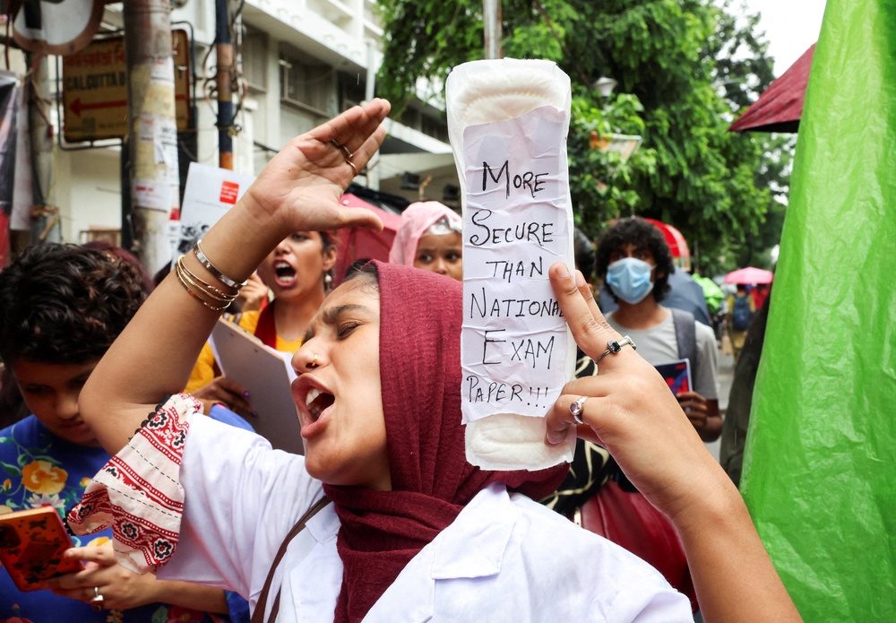 A woman holds a sanitary pad with a slogan in solidarity with India's Cockroach Janta Party protests held at Jantar Mantar in New Delhi (Reuters)