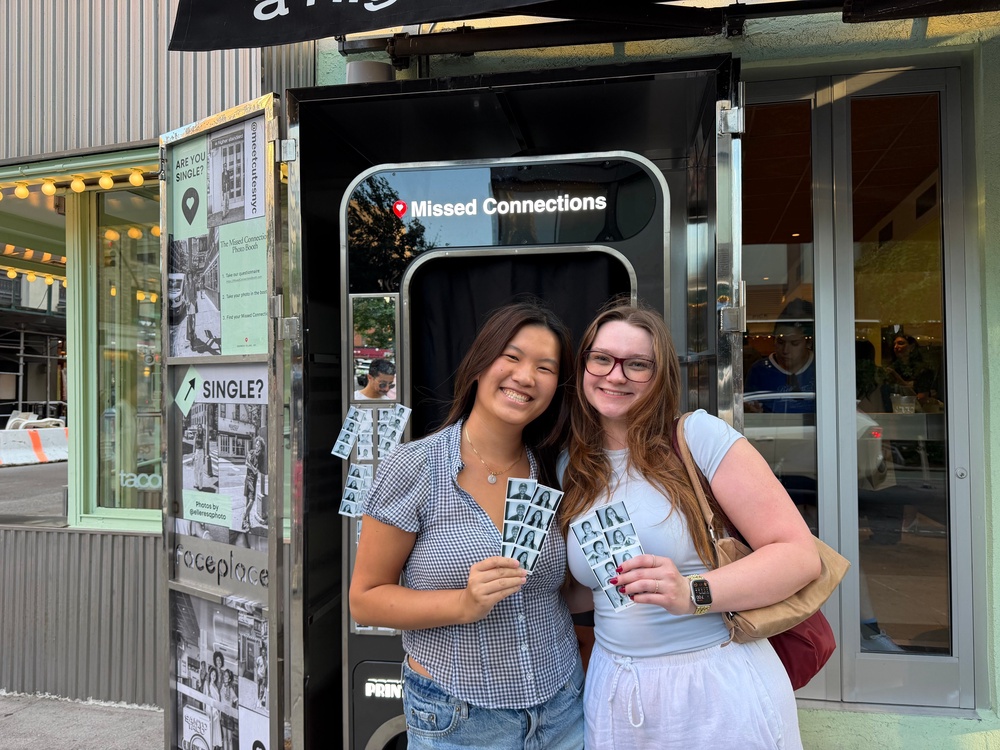 Cassidy (right) pictured with a friend after receiving their matches at the ‘Missed Connections’ photobooth (Ellie Muir / The Independent)