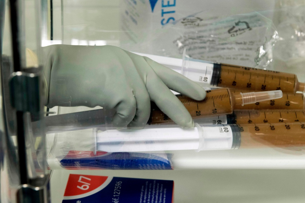 Laboratory technicians at the Centre Hospitalier Universitaire (CHU) prepare syringes with stool mixed in a solution to treat patients with serious infections of the colon by faecal microbiota transplantation (FMT) (AFP via Getty Images)