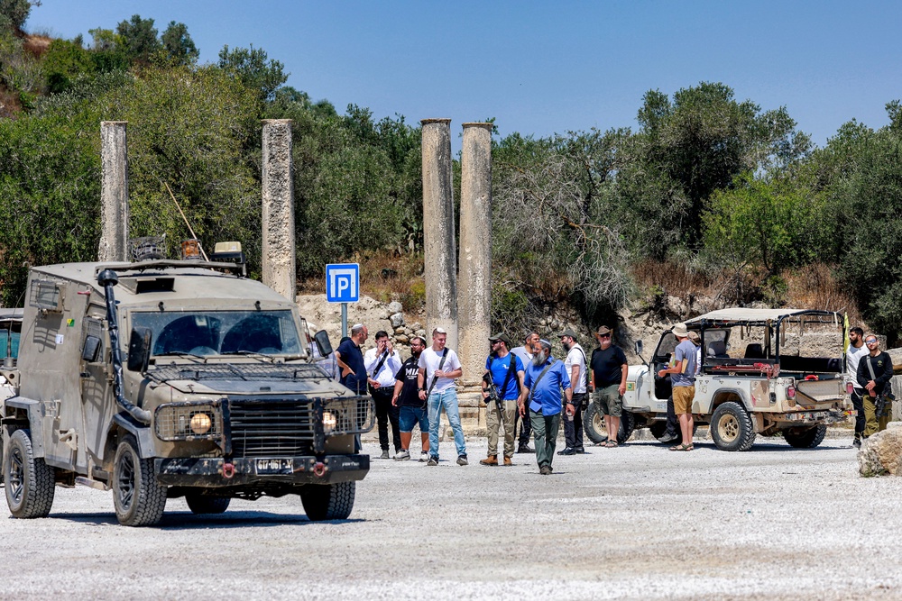 Israeli settlers are pictured near Israeli military vehicles during an official visit by a group of foreign diplomats accredited by the Palestinian Authority at the archaeological site of Sebastia, north of Nablus in the occupied West Bank, on June 29, 2026 (AFP/Getty)